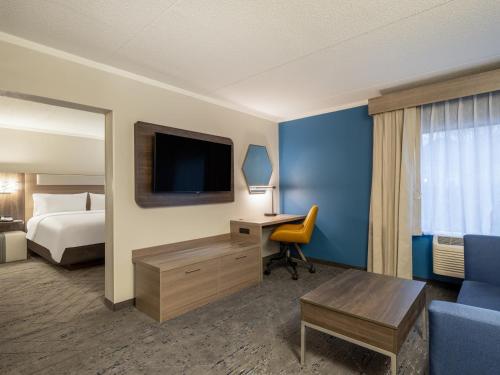 a hotel room with a bed and a desk with a television at Holiday Inn Express & Suites Greensboro - I-40 atWendover by IHG in Greensboro