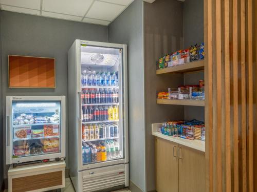 a kitchen with an open refrigerator and shelves of drinks at Holiday Inn Express & Suites Greensboro - I-40 atWendover by IHG in Greensboro