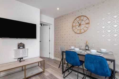 a dining room with a table and chairs and a clock at The Honeycomb Residence by Fortuna Property Portfolio in Cheltenham