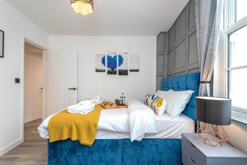 a bedroom with a bed with a blue headboard at The Honeycomb Residence by Fortuna Property Portfolio in Cheltenham