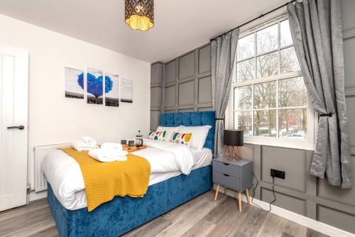 een slaapkamer met een blauw en wit bed en een raam bij The Honeycomb Residence in Cheltenham