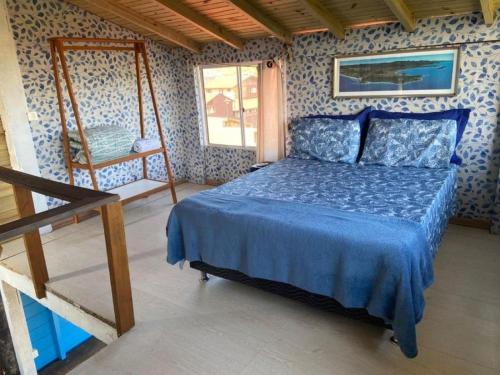 een slaapkamer met een bed met een blauwe sprei bij Essência da Guarda Surf House in Guarda do Embaú