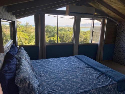 1 dormitorio con 1 cama en una habitación con ventanas en Essência da Guarda Surf House en Guarda do Embaú