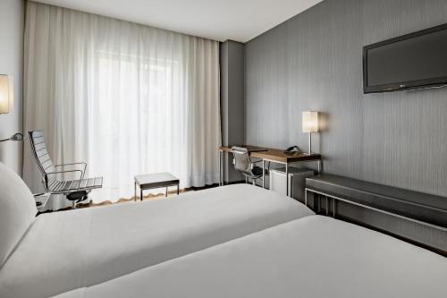 ブルゴスにあるAC Hotel Burgos by Marriottの大型ベッドとテレビが備わるホテルルームです。