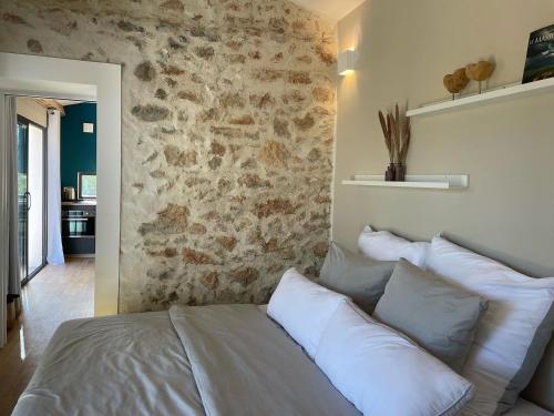 un lit dans une chambre avec un mur en pierre dans l'établissement Eva's Cabanon, à Cabasse
