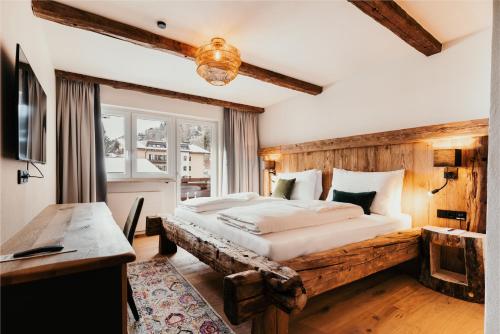 a bedroom with a large bed with a wooden headboard at Dorfhotel Glücksschmiede in Saalbach Hinterglemm