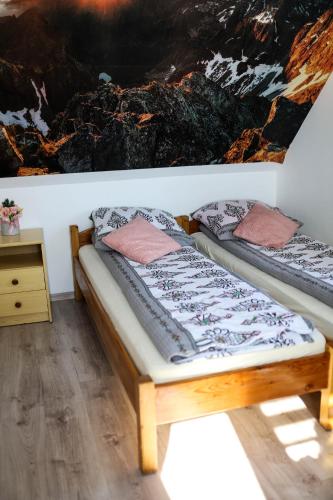 two beds in a room with a painting on the wall at Domek JuKa in Biały Dunajec