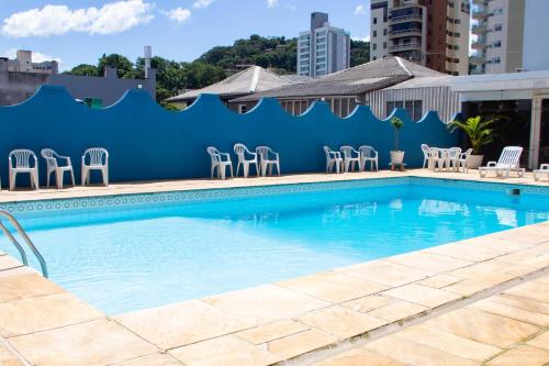 a swimming pool with chairs and a blue wall at HOTEL DOMHOF in Blumenau