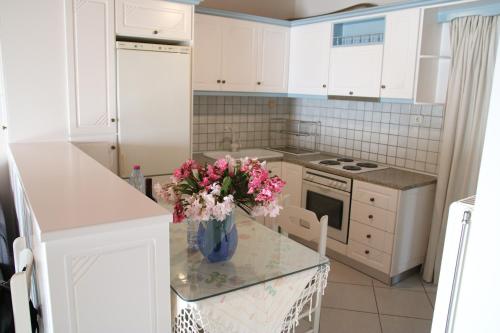eine Küche mit weißen Schränken und einer Vase aus Blumen auf dem Tisch in der Unterkunft Eleftheria in Menídion