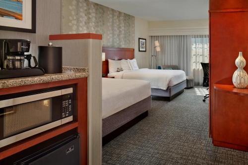 a hotel room with two beds and a microwave at Courtyard by Marriott Stuart in Stuart