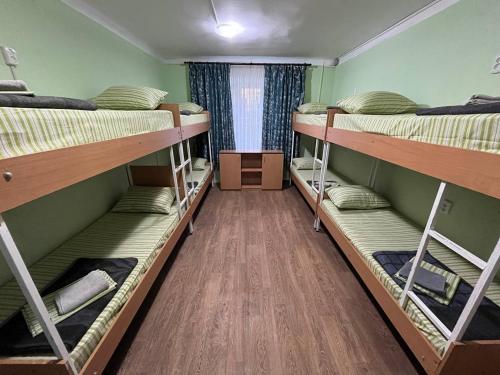 a dorm room with three bunk beds and a wooden floor at FOX Hostel Kyiv in Kyiv