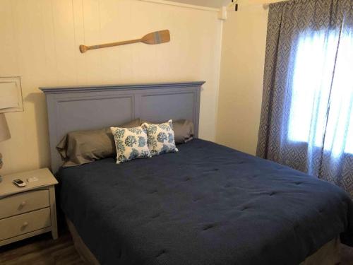 a bedroom with a bed with a blue blanket and a window at Lakefront Cabin - Texoma Coast - 14 in Mead