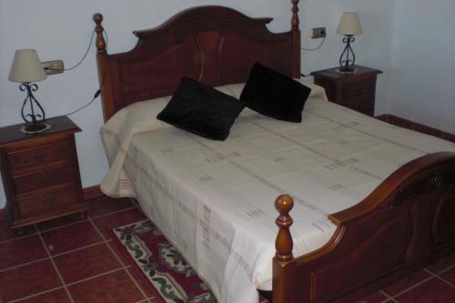 エル・チョロにあるCasa Rural El Puertoのベッド1台(上に黒い枕2つ付)