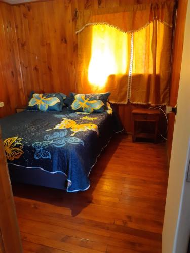 a bedroom with a bed with a blue comforter at Cabaña Eduvina in Choshuenco