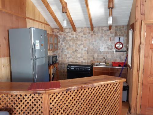 a kitchen with a refrigerator and a table in it at Cabaña Eduvina in Choshuenco
