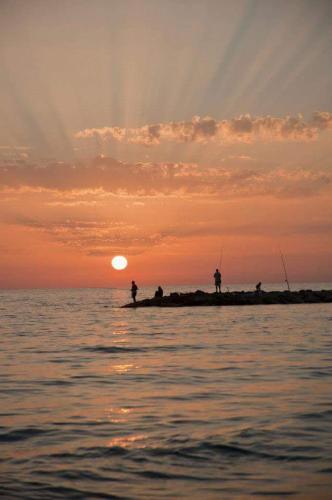 people fishing on a pier in the ocean at sunset at Serpa Hotel in Anzio