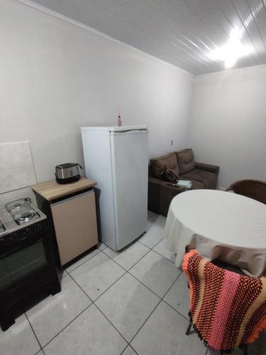 a kitchen with a white refrigerator and a couch at Apartamento privativo 06 in Blumenau