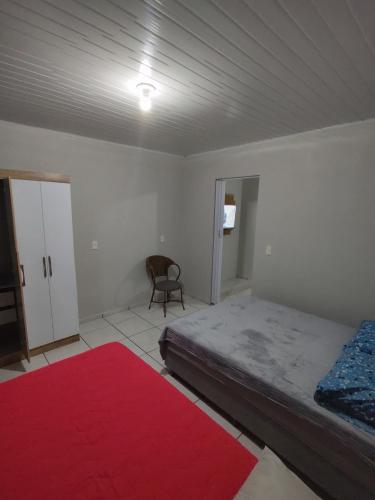 a bedroom with a bed and a red rug at Apartamento privativo 06 in Blumenau