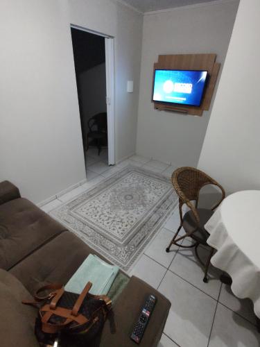 a living room with a couch and a flat screen tv at Apartamento privativo 06 in Blumenau