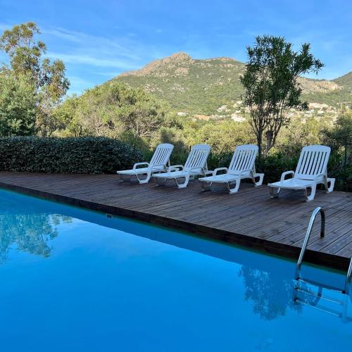 a group of chairs sitting on a wooden deck next to a swimming pool at Chez Mina in Lumio