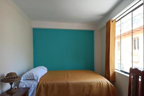 Un dormitorio con una pared azul y una cama en Casa D´Maria, en Ollantaytambo