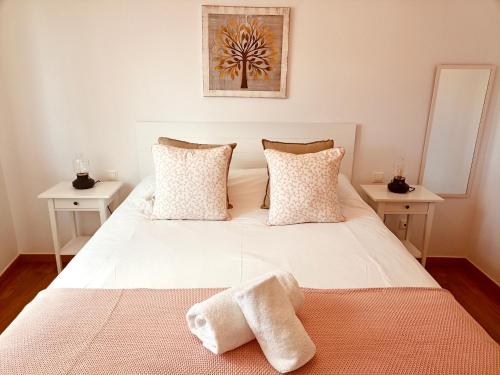 1 dormitorio con 1 cama blanca y 2 toallas en Apartamento Little Xoan, en Poio
