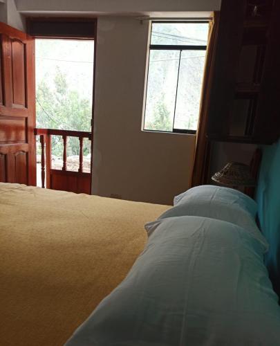 a bed in a bedroom with two windows and a bed sidx sidx sidx at Casa D´Maria in Ollantaytambo