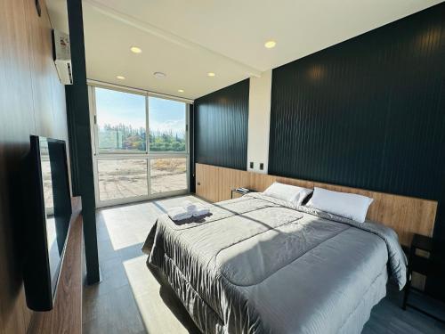 a bedroom with a large bed and a large window at Cubos de Chacras in Ciudad Lujan de Cuyo