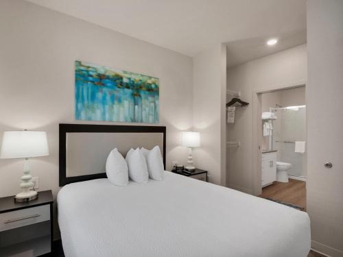 a bedroom with a white bed with two lamps at WaterWalk Extended Stay by Wyndham Charlotte - Arrowood in Charlotte