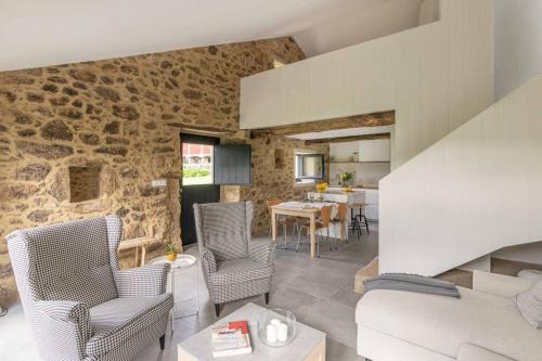 uma sala de estar e de jantar com uma parede de pedra em A casa de Abaixo, aloxamento rural em Vedra