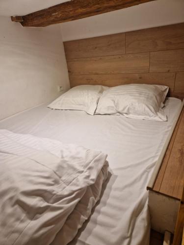 un lit avec des draps blancs et des oreillers dans une chambre dans l'établissement Gîte 