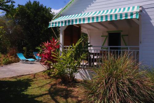a white house with a green and white awning at Gîtes de la coulisse in Trois-Rivières