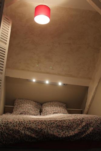 ein Schlafzimmer mit einem Bett mit einer roten Lampe darüber in der Unterkunft La laiterie du Moulin in Montivilliers