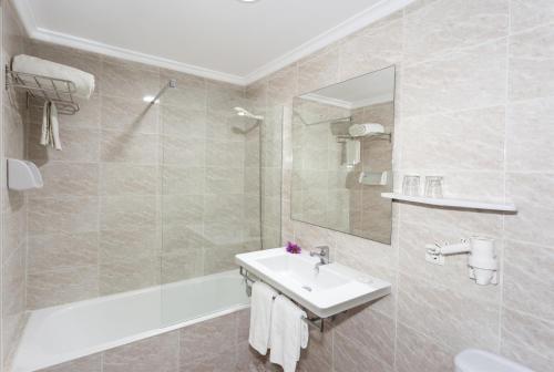 a bathroom with a sink and a tub and a mirror at Hotel Venecia Paguera in Paguera