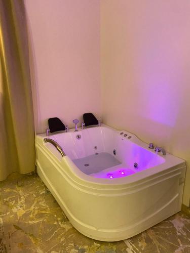 jacuzzi con luces púrpuras en una habitación en Hotel Rest en Abū Qa‘ar