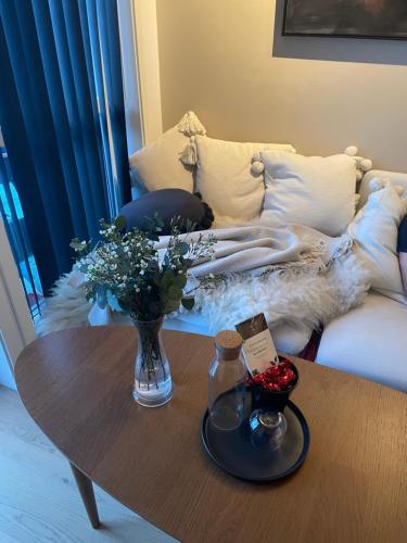 a coffee table with a vase of flowers and a couch at Leilighet sentralt i Tromsø in Tromsø