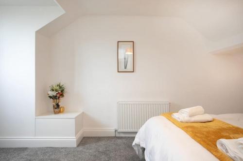 a white bedroom with a bed and a vase of flowers at Cudworth House, Barnsley for contractors & Families, off-road parking, speedy WIFI,etc in Barnsley