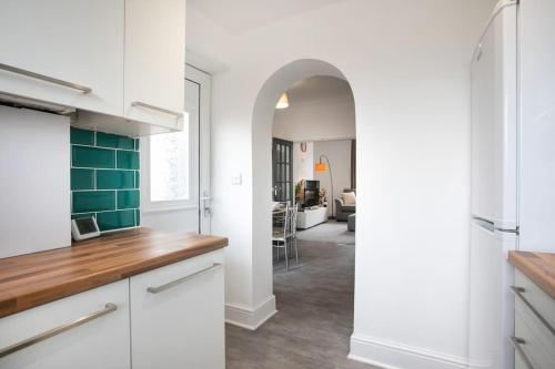 a kitchen with white cabinets and a green tile hallway at Cudworth House, Barnsley for contractors, families & Biz in Barnsley