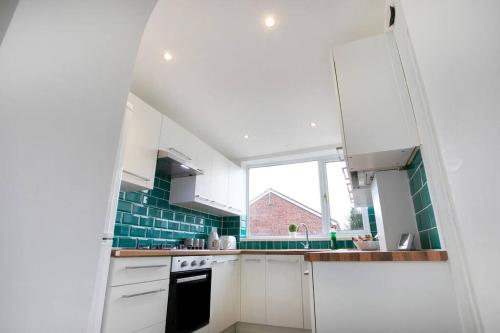 a small kitchen with white cabinets and a window at Cudworth House, Barnsley for contractors & Families, off-road parking, speedy WIFI,etc in Barnsley