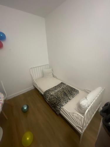 un letto bianco in una stanza con una palla sul pavimento di Appartement chez mounir a Massy