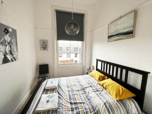 Un dormitorio con una cama con almohadas amarillas y una ventana en On the Quay, en Harwich