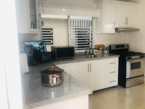 a kitchen with white cabinets and a pot on the counter at Casa en Baní cerca de playa los almendros in Baní