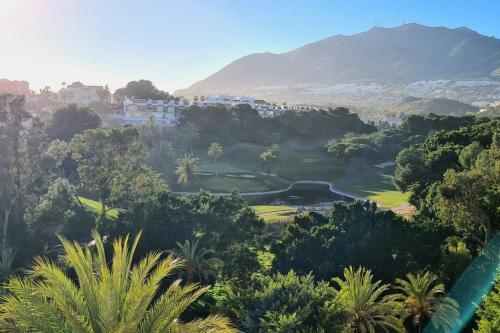 uitzicht op een golfbaan met bomen en bergen bij Soleado apartamento Golf y a 900 m de la playa in Benalmádena