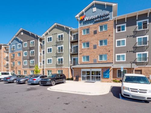 un edificio de apartamentos con coches aparcados en un aparcamiento en Waterwalk Charlotte Arrowood en Charlotte