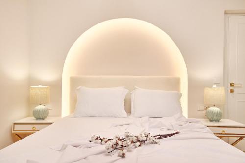 een wit bed met een wit hoofdeinde en bloemen erop bij Blush & Crema Apartments in Zakynthos