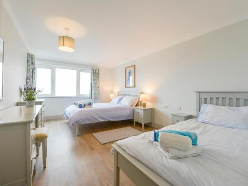 a white bedroom with two beds and a desk at 17 Burgh Island Causeway in Kingsbridge
