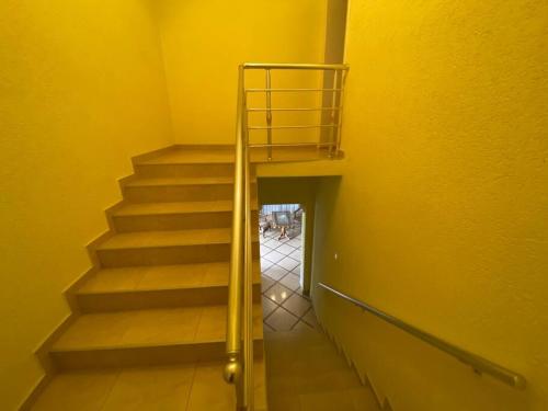 a staircase in a yellow room with a metal railing at Vila Arapovi - Bosilovo in Strumica
