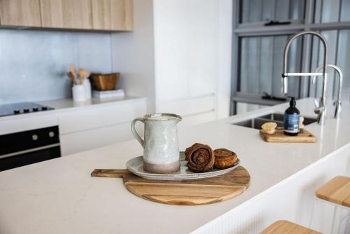 a kitchen counter with a jug and some donuts on a plate at 101 on the Beach Jervis Bay in Huskisson