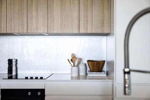 a kitchen counter with wooden cabinets and a sink at 101 on the Beach Jervis Bay in Huskisson