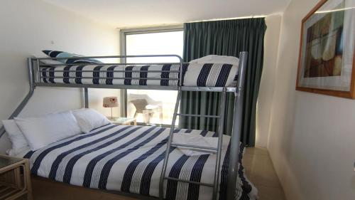 two bunk beds in a room with a window at Ebbtide 13 in Forster